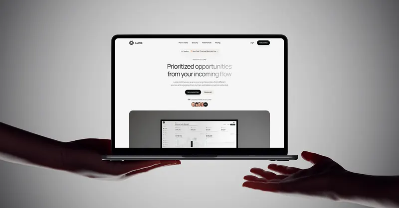 Luma landing page on a laptop passed from one hand to another against a grey backdrop